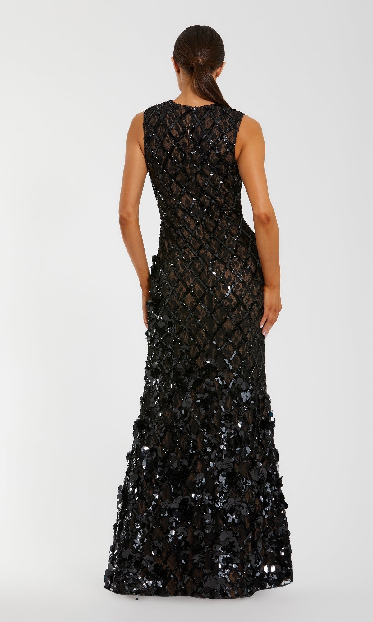 A person stands facing away in the Mac Duggal 94277 long black beaded formal dress with a geometric pattern, hair styled in a low sleek ponytail.